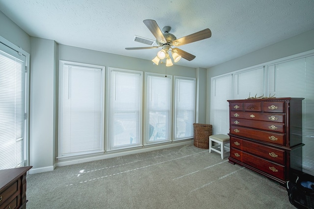 bedroom with a ceiling fan, visible vents, carpet floors, and a textured ceiling