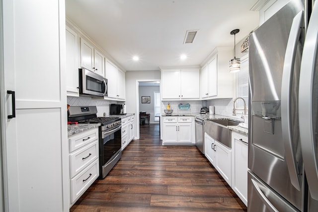 kitchen with visible vents, light stone countertops, dark wood finished floors, appliances with stainless steel finishes, and a sink