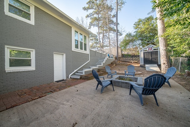 view of patio with an outbuilding, a storage unit, fence, and a fire pit