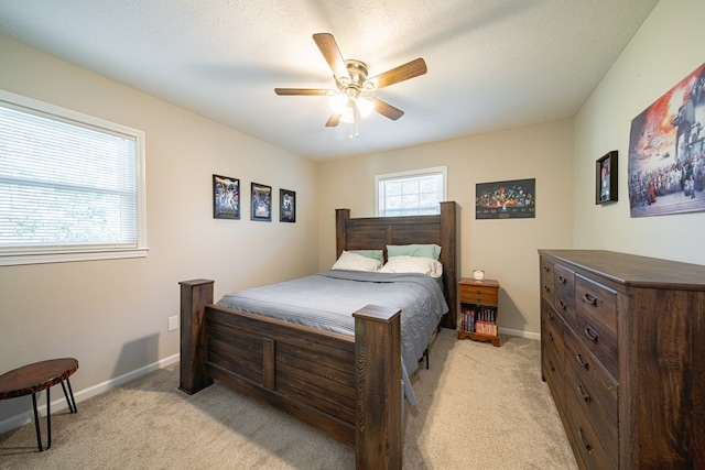 bedroom featuring light colored carpet, a textured ceiling, a ceiling fan, and baseboards