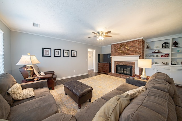 living area with visible vents, a brick fireplace, crown molding, wood finished floors, and a textured ceiling