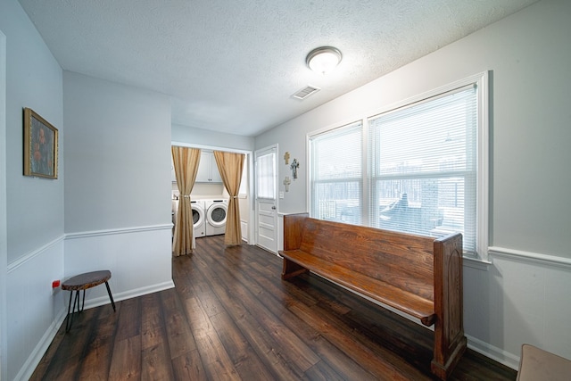 interior space featuring dark wood-style floors, baseboards, visible vents, a textured ceiling, and washing machine and dryer