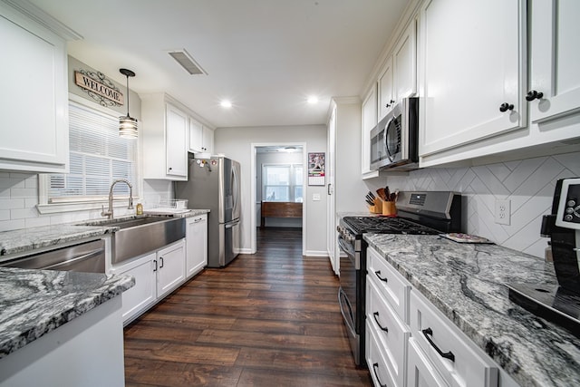 kitchen featuring light stone counters, visible vents, dark wood finished floors, a sink, and appliances with stainless steel finishes