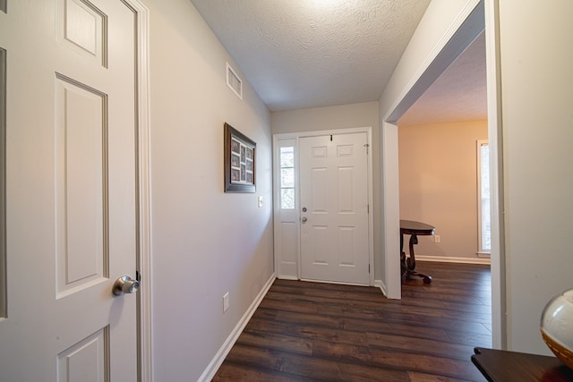 entrance foyer with dark wood finished floors, visible vents, a textured ceiling, and baseboards