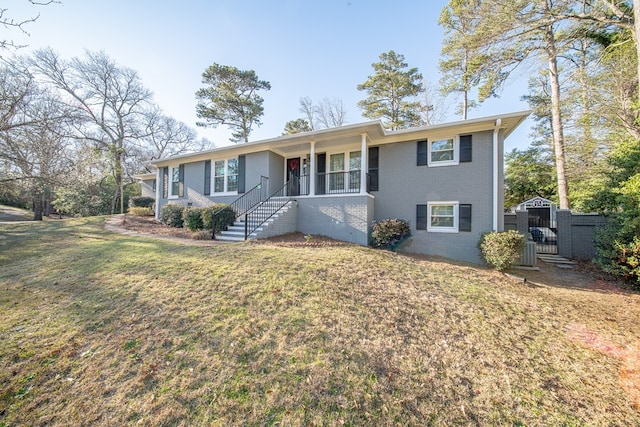 single story home featuring brick siding, a front yard, and a gate