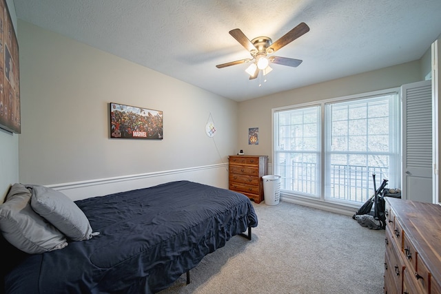 bedroom with light colored carpet, a textured ceiling, and a ceiling fan