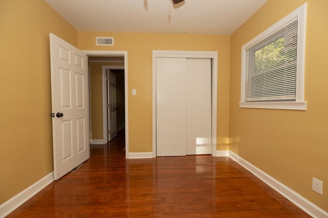 unfurnished bedroom with baseboards, a closet, visible vents, and wood finished floors