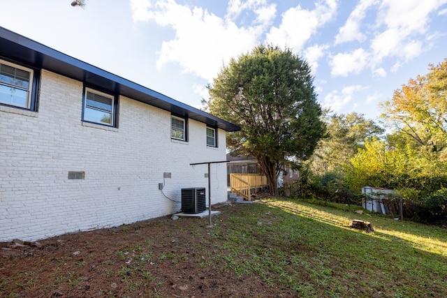 view of property exterior featuring central AC, brick siding, and a lawn