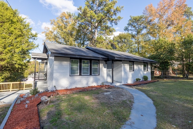 view of front of property with brick siding, a front lawn, and fence