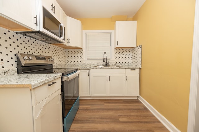 kitchen featuring electric stove, tasteful backsplash, a sink, wood finished floors, and baseboards