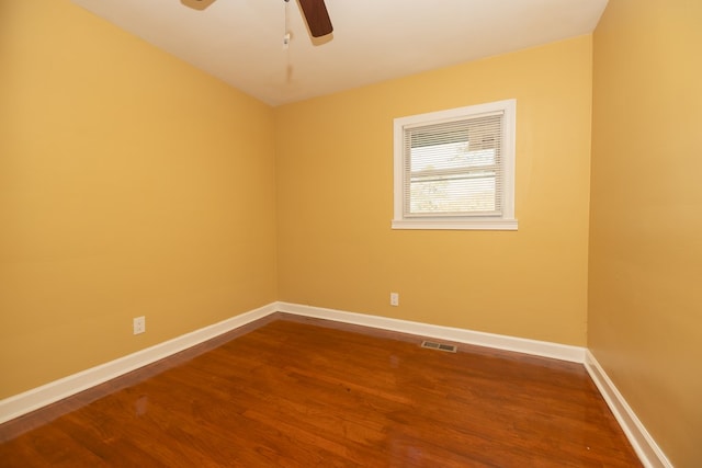 empty room with visible vents, baseboards, dark wood finished floors, and a ceiling fan