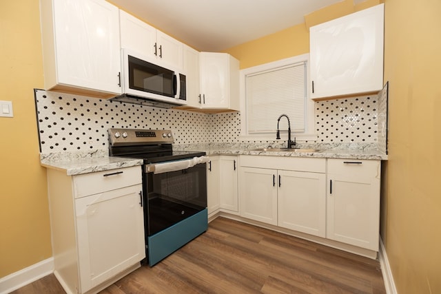 kitchen featuring electric range, backsplash, a sink, and white microwave