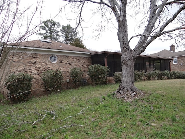 exterior space with brick siding, a front lawn, and a sunroom