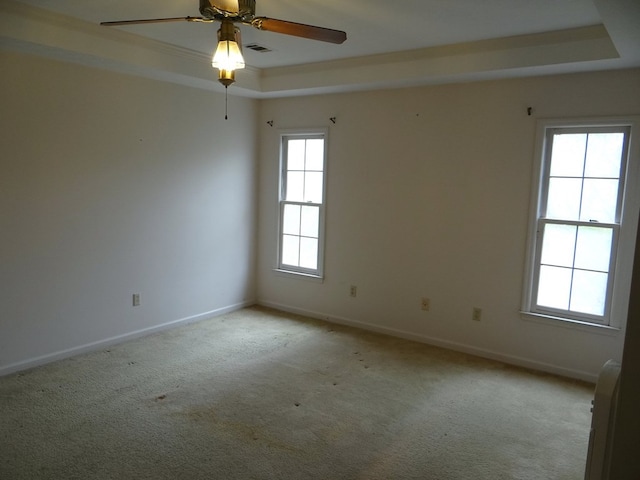 unfurnished room with a ceiling fan, visible vents, baseboards, light carpet, and a raised ceiling