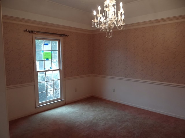 carpeted empty room with a wealth of natural light, a wainscoted wall, a notable chandelier, and wallpapered walls