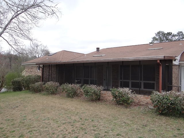 back of house with brick siding, a lawn, and a sunroom