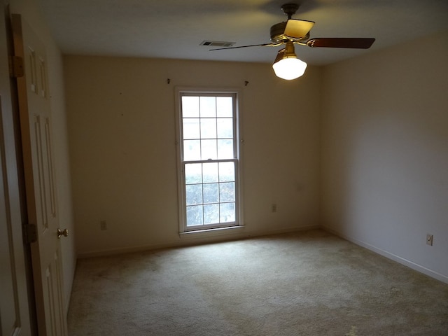 empty room featuring visible vents, carpet floors, baseboards, and ceiling fan