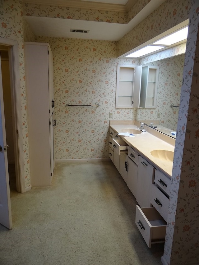 full bathroom with visible vents, wallpapered walls, double vanity, carpet flooring, and a sink