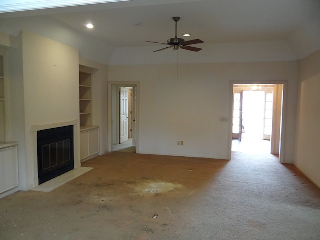 unfurnished living room with built in features, a ceiling fan, a tray ceiling, a fireplace with flush hearth, and recessed lighting