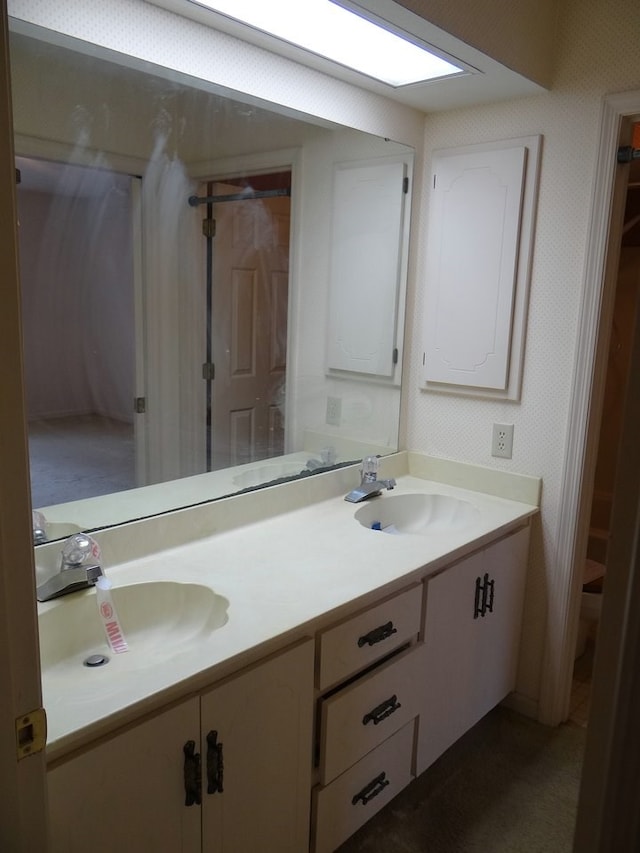 bathroom with a sink, double vanity, and wallpapered walls