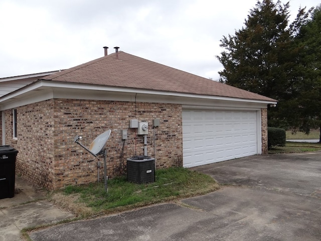 view of side of property with aphalt driveway, brick siding, and a garage