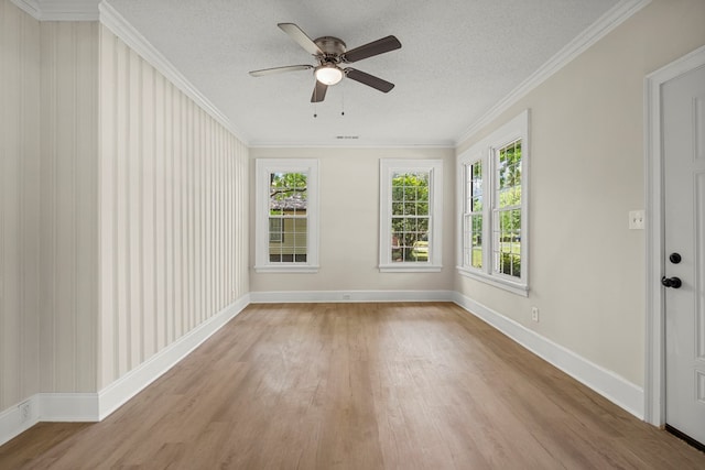 empty room with ornamental molding, light wood finished floors, a ceiling fan, and baseboards