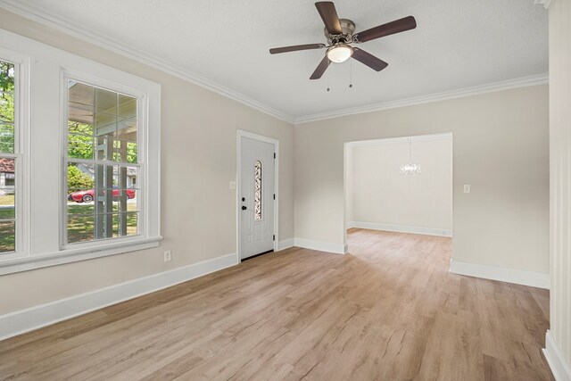 spare room with ornamental molding, ceiling fan with notable chandelier, baseboards, and light wood-style floors