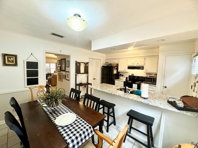 tiled dining space with sink and a textured ceiling