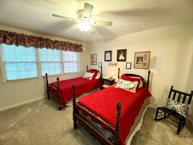 bedroom with ceiling fan, carpet floors, and a textured ceiling