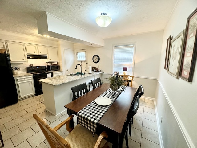 dining space with sink, light tile patterned flooring, and a textured ceiling