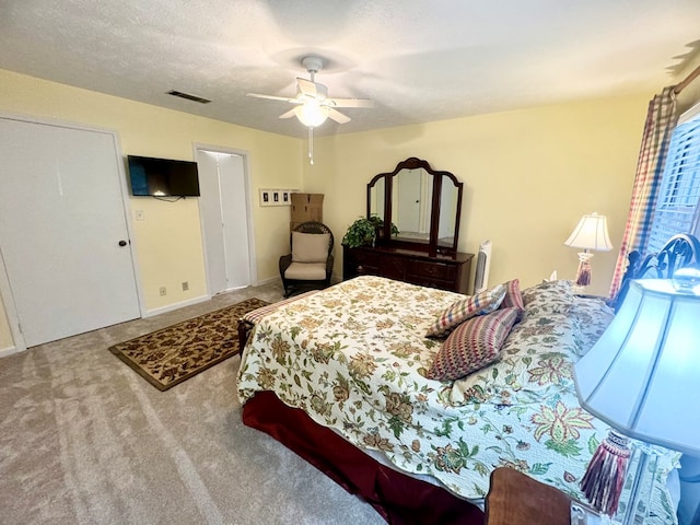 carpeted bedroom featuring ceiling fan and a textured ceiling