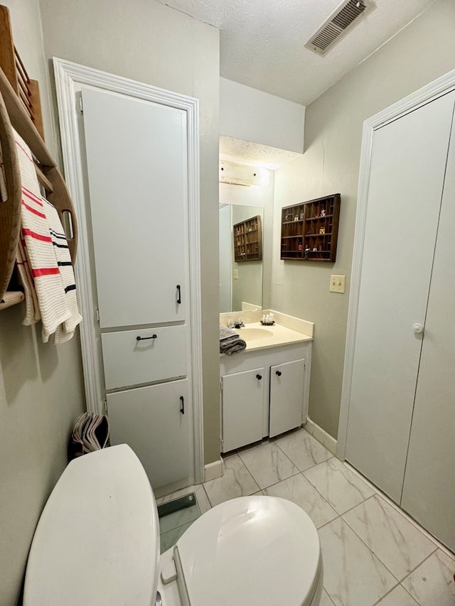 bathroom with vanity, a textured ceiling, and toilet