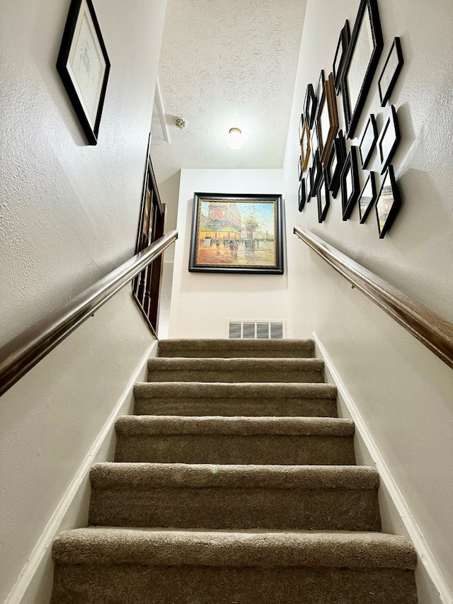 stairway featuring a textured ceiling