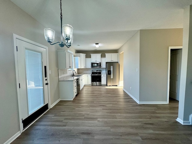 kitchen with white cabinetry, dark wood-type flooring, stainless steel appliances, a notable chandelier, and pendant lighting