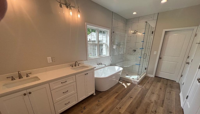full bath featuring a sink, a soaking tub, a shower stall, and wood finished floors