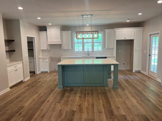kitchen featuring a sink, wood finished floors, white cabinets, and tasteful backsplash