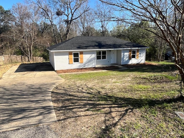 view of front of property with concrete driveway, a front yard, and fence