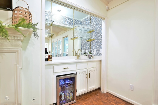 bar featuring baseboards, a sink, and beverage cooler