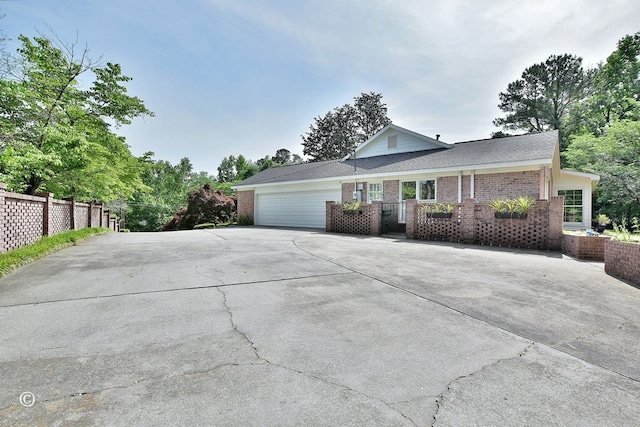 view of front of property with concrete driveway, brick siding, fence, and an attached garage