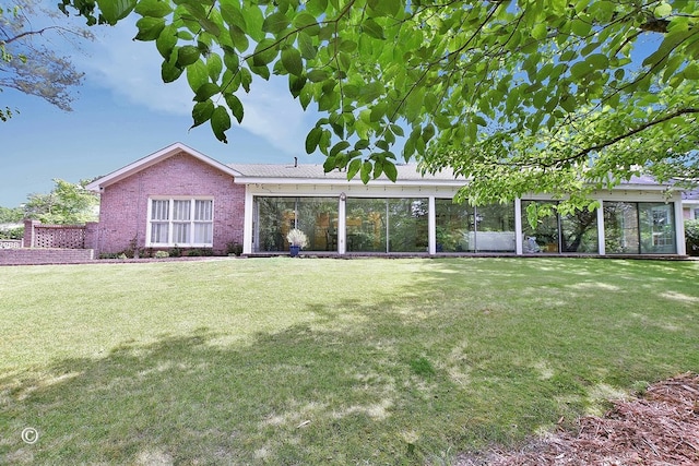 view of front of home with a sunroom, a front lawn, and brick siding