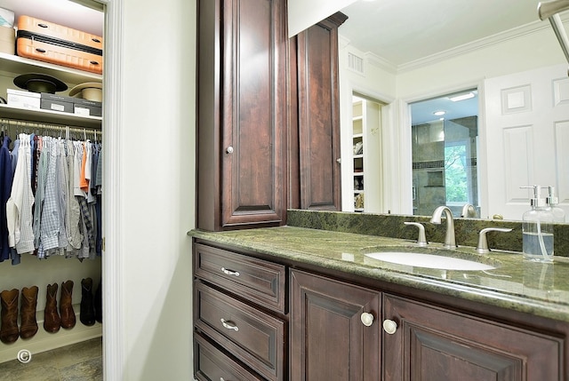 full bath with walk in shower, vanity, visible vents, crown molding, and a walk in closet