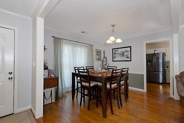 dining space with crown molding, baseboards, a chandelier, and light wood-type flooring