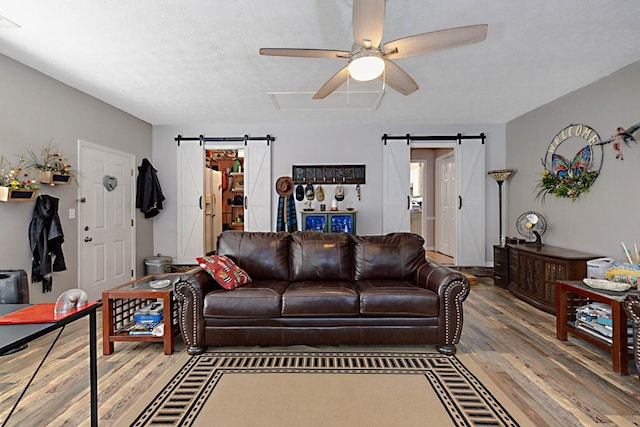 living area featuring a ceiling fan, a barn door, and wood finished floors
