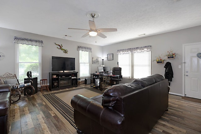 living area with visible vents, a ceiling fan, and dark wood-type flooring
