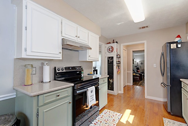 kitchen with light wood finished floors, light countertops, stainless steel appliances, under cabinet range hood, and visible vents
