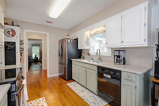 kitchen featuring appliances with stainless steel finishes, a sink, light countertops, light wood-style floors, and a wealth of natural light