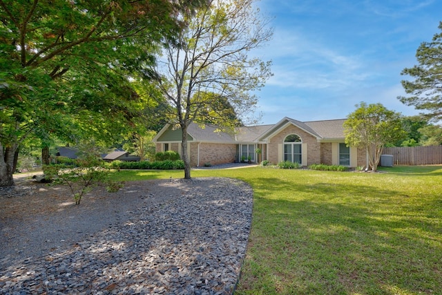 ranch-style home with brick siding, fence, and a front lawn