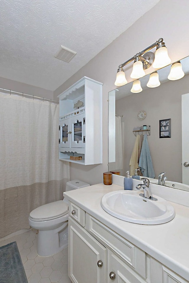 full bathroom with tile patterned flooring, visible vents, vanity, toilet, and a textured ceiling