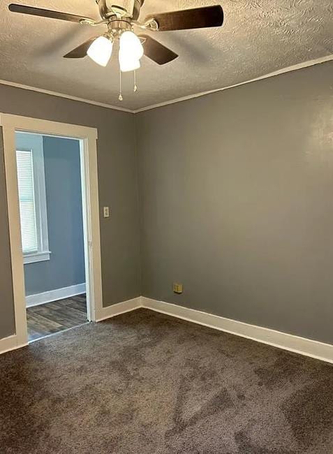 unfurnished room with a textured ceiling, dark carpet, ceiling fan, and ornamental molding