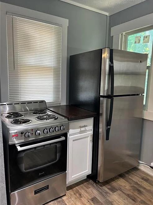 kitchen with white cabinets, appliances with stainless steel finishes, light wood-type flooring, and a textured ceiling